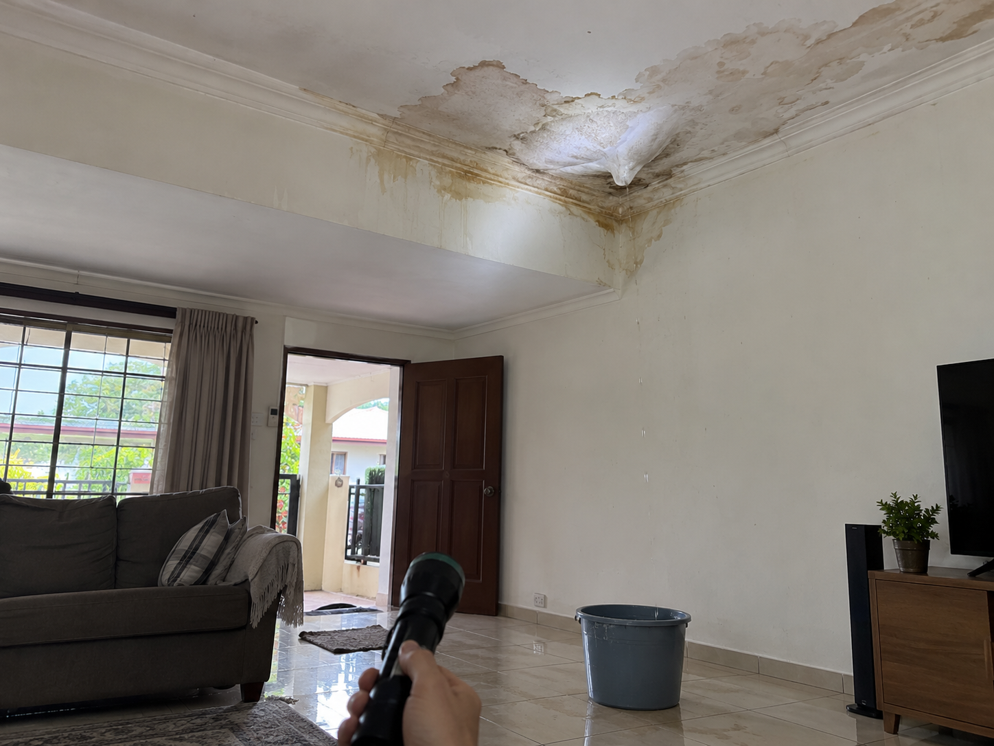 Tompok air di siling rumah teres diperiksa dengan lampu suluh